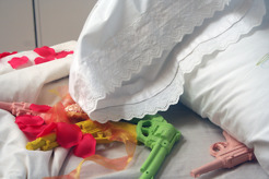 <p>"Forced Removal" 2003/4 &nbsp;(detail) Size variable.</p>
<p>Pillow, embroidered pillowcase, &nbsp;bedding, silicone guns, salt, &nbsp;silk rose pettals, &nbsp;ribbons, holster made of &nbsp;silk roses.</p>